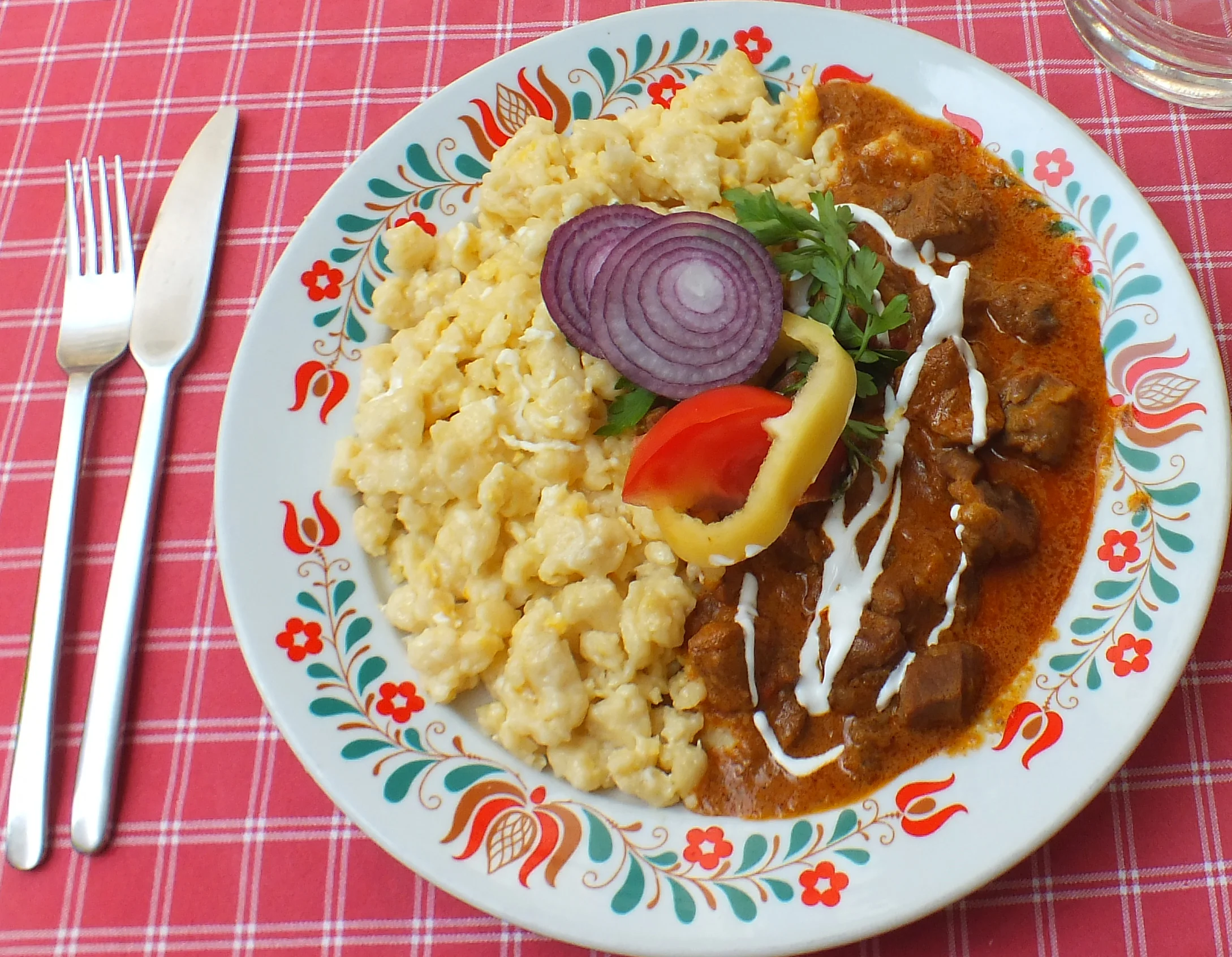 Pörkölt nokedlivel és friss zöldségekkel, népi mintás tányéron